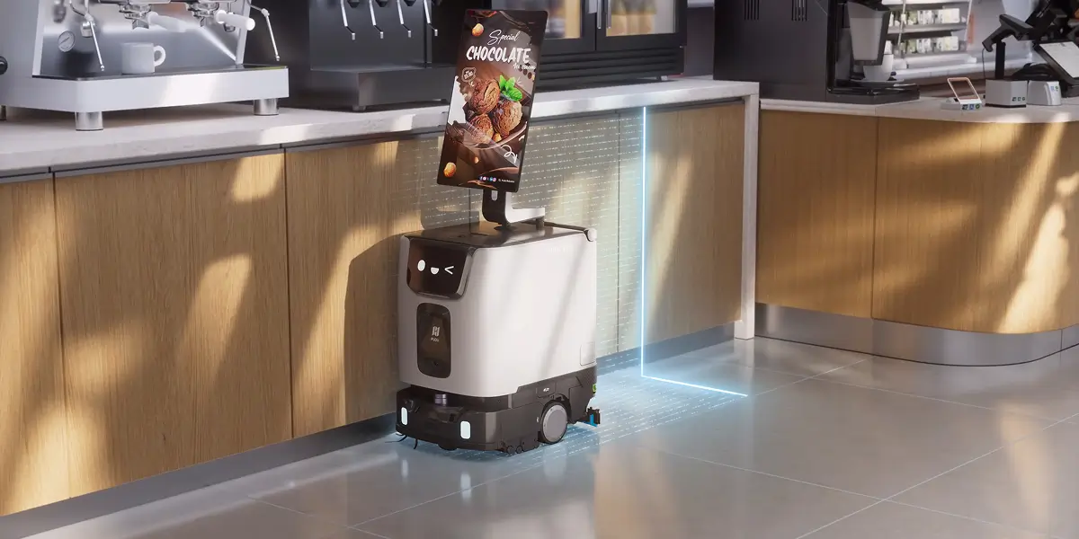 Kafe tezgahının önünde reklam ekranıyla çalışan Pudu ET1 temizlik robotu