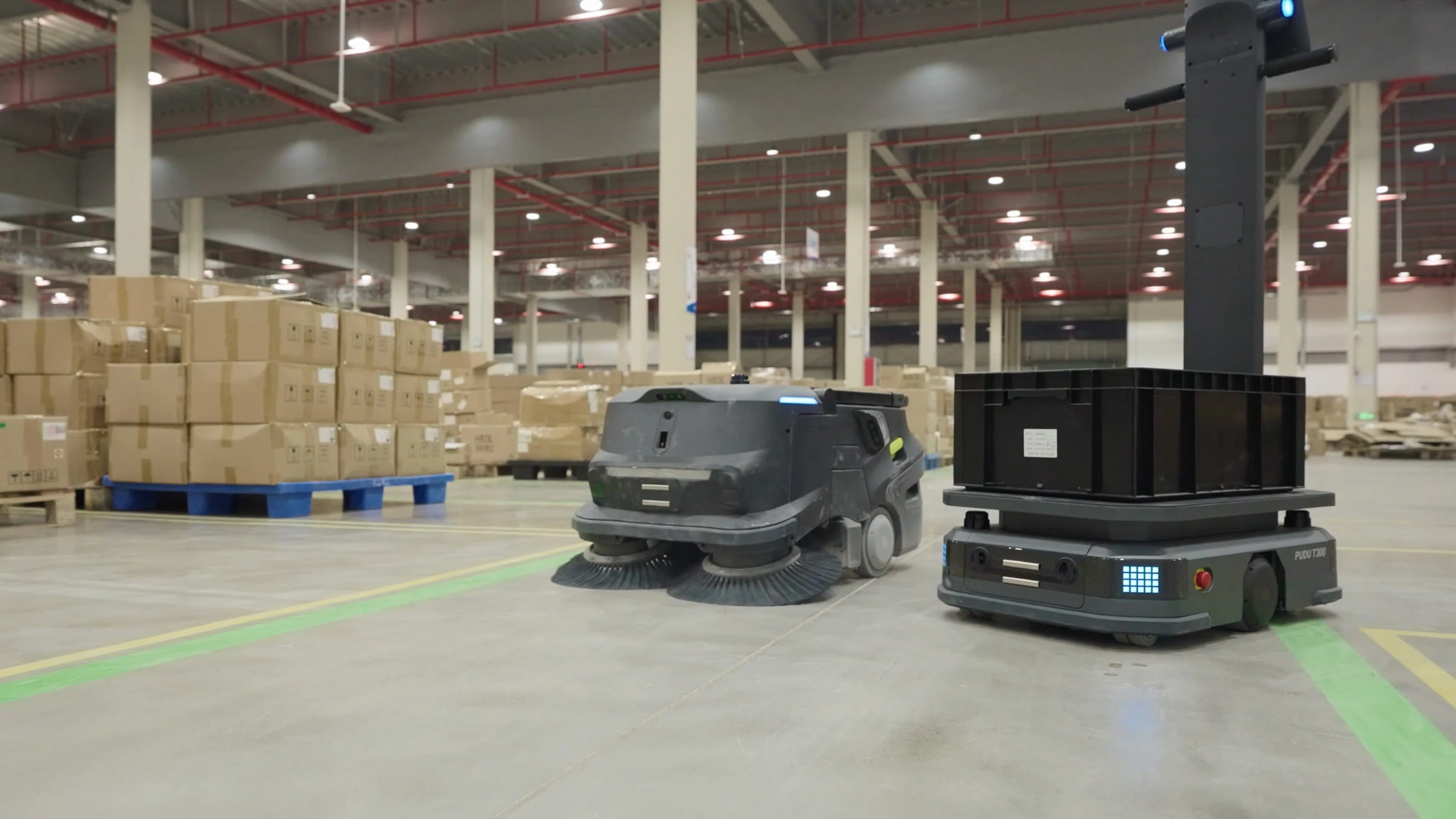 Depoda koli yığınlarının önünde endüstriyel temizlik robotu ve taşıma robotu