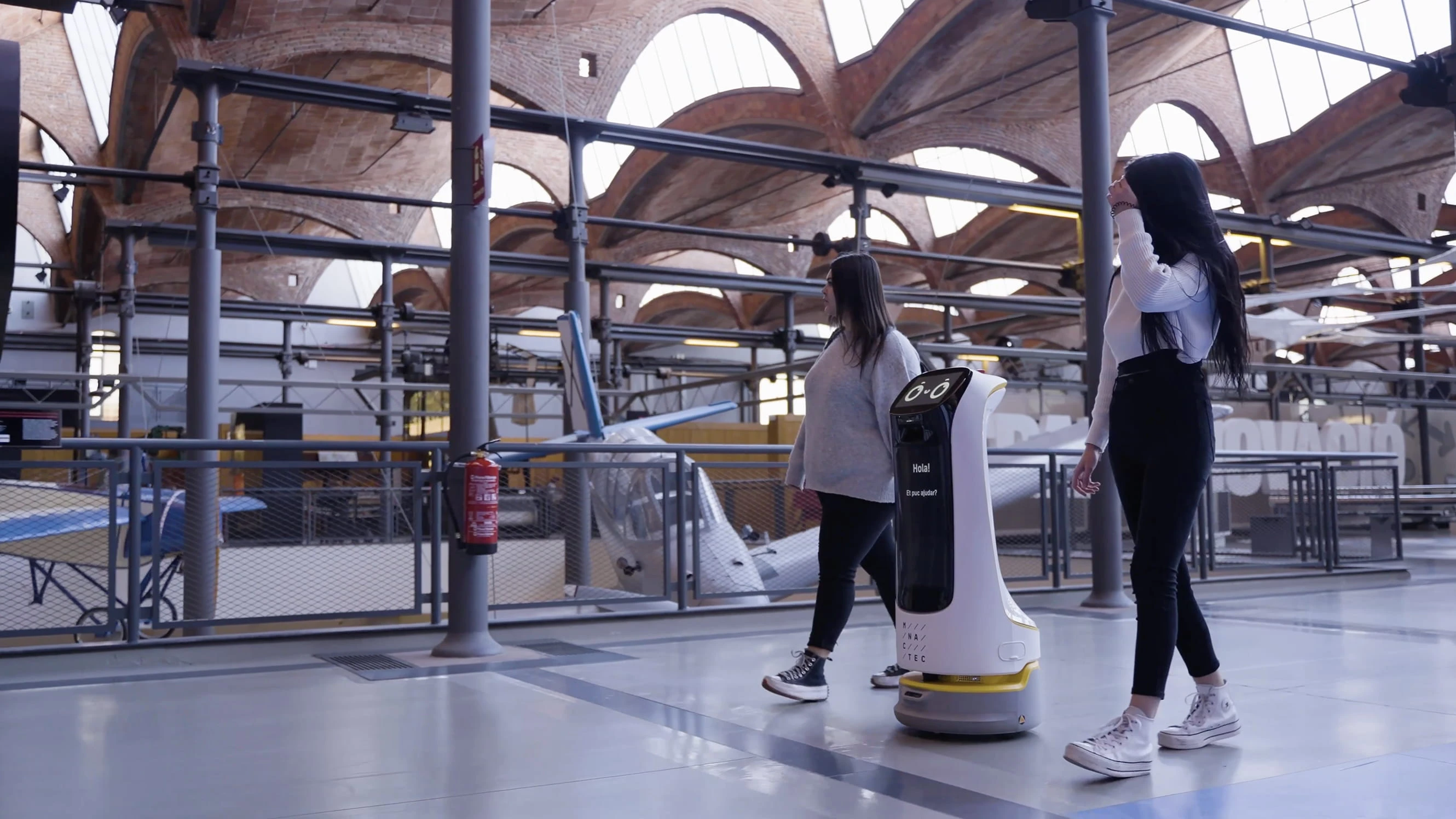 Kapalı bir salonda iki ziyaretçiye eşlik eden karşılama robotu