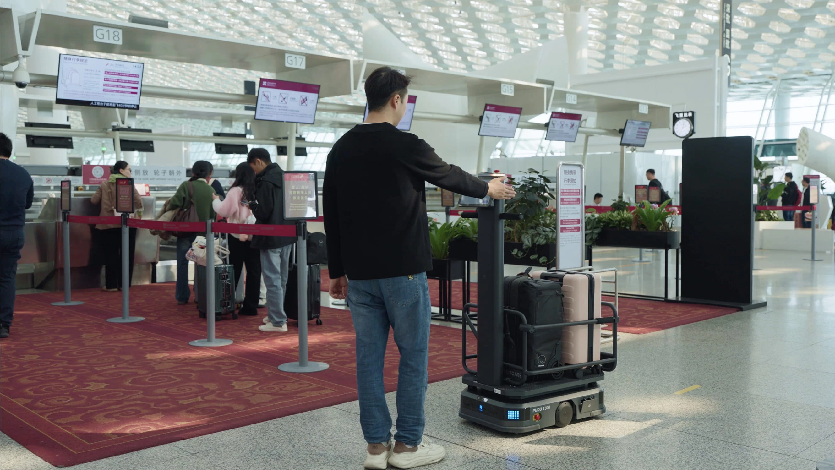 Havalimanı check-in alanında bagaj taşıma robotunu yönlendiren bir yolcu